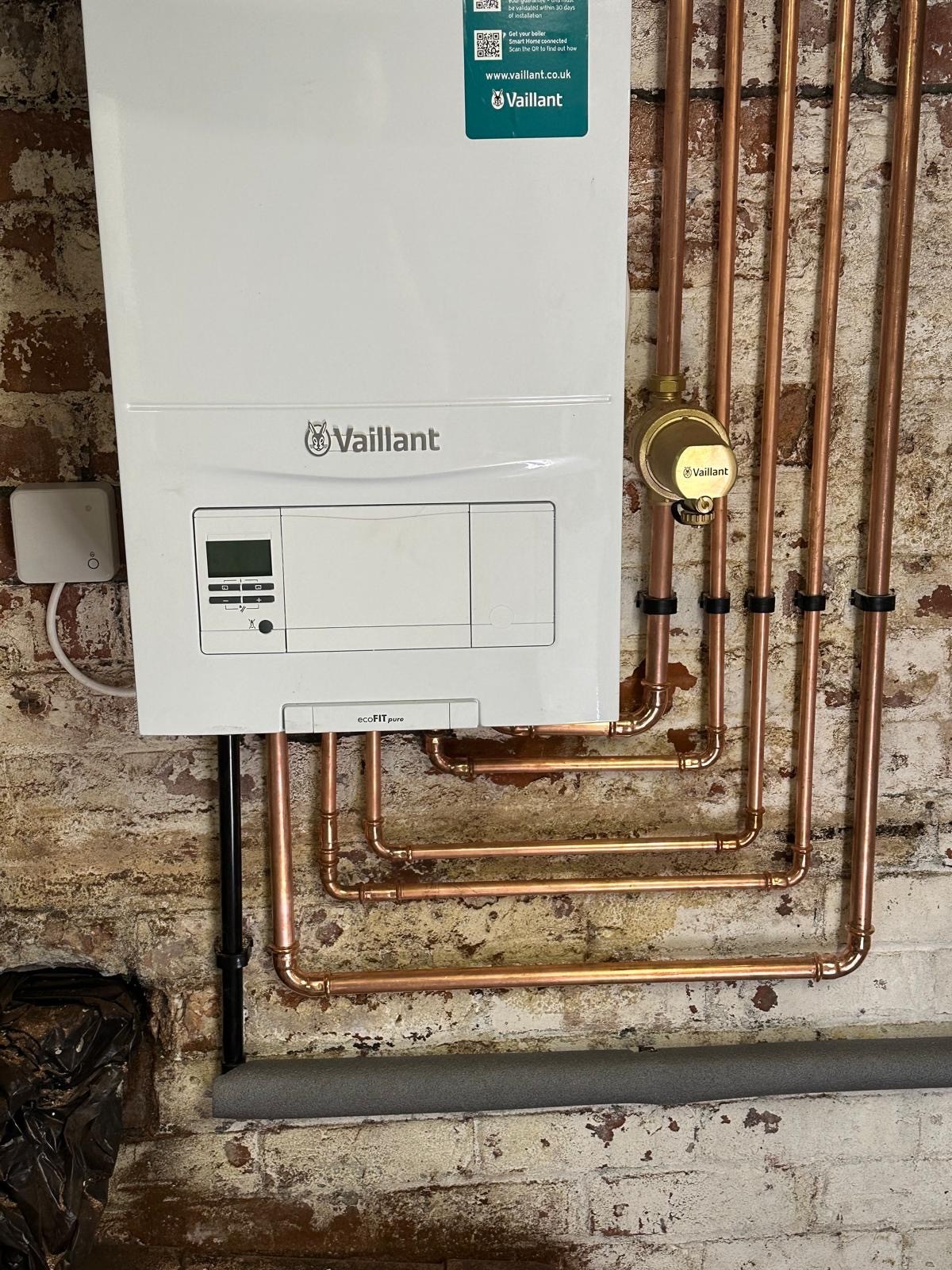 Vaillant boiler installation with rebuilt copper pipework on an exposed brick wall in Manchester
