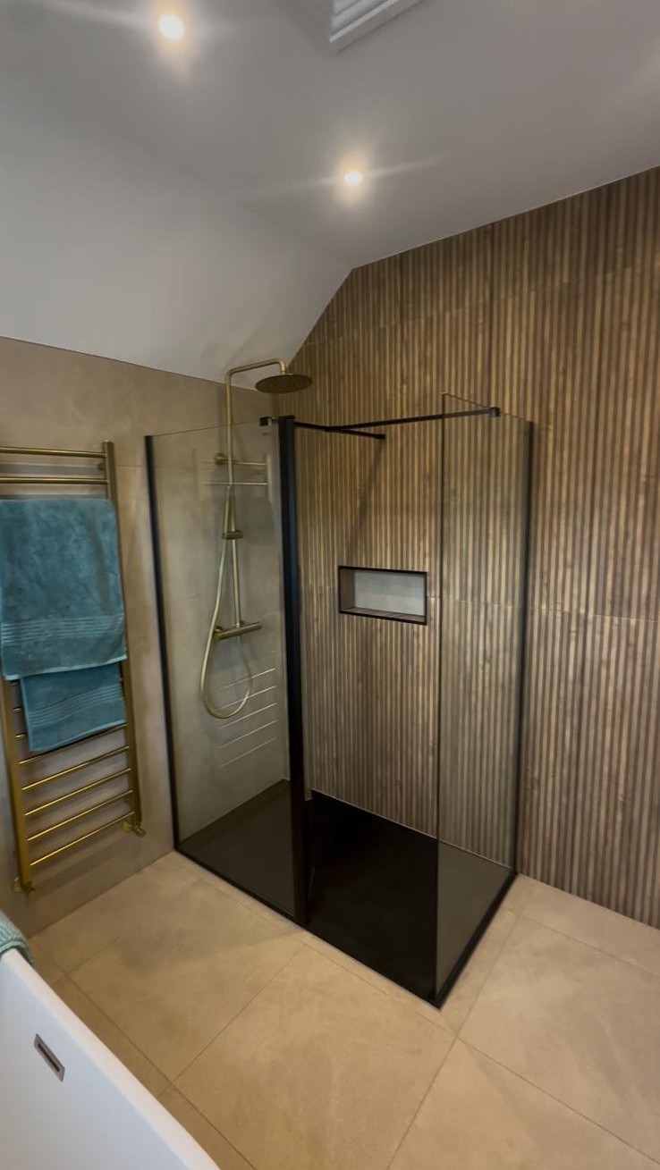 Completed bathroom installation in Manchester with walk-in glass shower enclosure and brass fittings