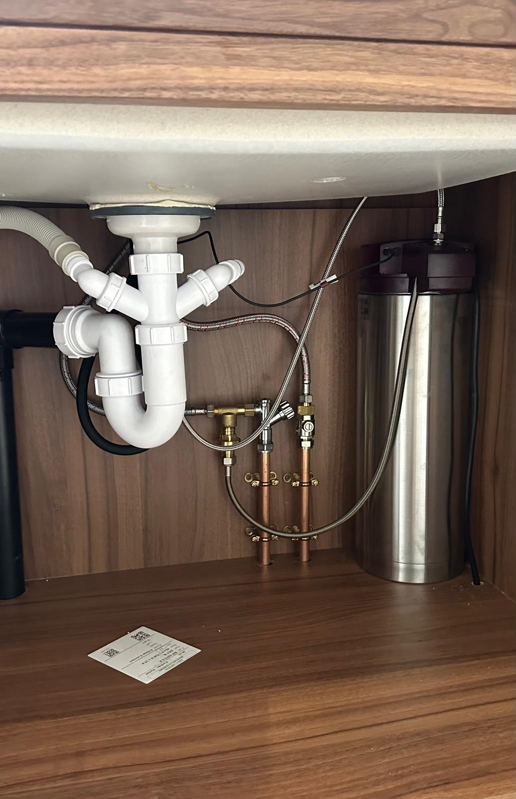 Under-sink plumbing with new waste trap and boiling water tap unit fitted in a Manchester kitchen
