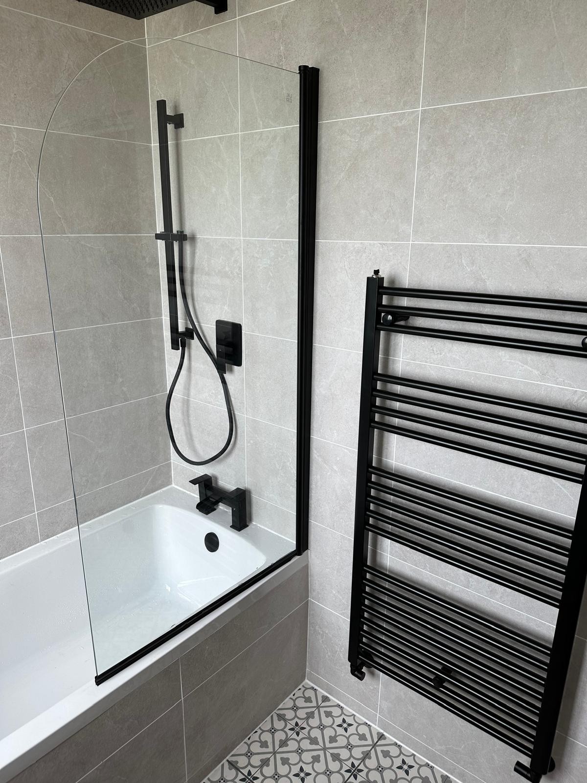Bath with glass screen, shower column and heated towel radiator installed in a Manchester bathroom